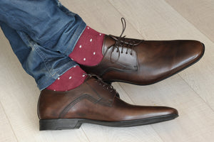 Man wearing burgundy socks with brown shoes and jeans