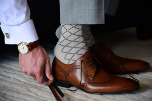 Man wearing unique and elegant dress socks with orange polka dots and matching accessories
