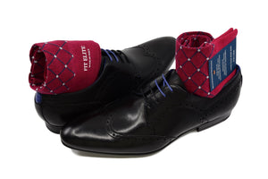 Men's colorful dress socks, red with grey polka dots, displayed inside black shoes