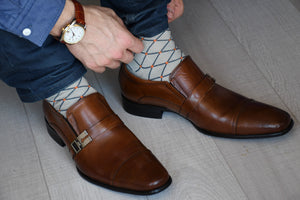 Man wearing luxury cotton socks, grey with orange polka dots matching brown shoes