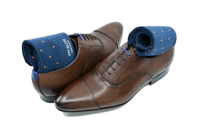 Men's navy blue dress socks with orange polka dots by Fit Elite displayed inside brown dress shoes