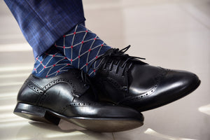 Men's navy dress socks patterned with red polka dots, matching navy blue pants