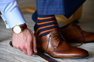 Men's colorful navy blue and orange striped dress socks with brown shoes