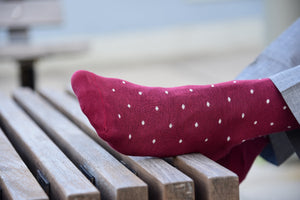 Man wearing burgundy polka dot socks with matching grey trousers