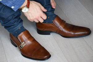 Man wearing blue and orange polka dot socks with matching blue jeans and brown dress shoes